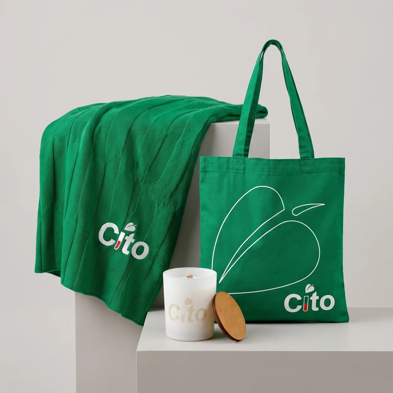 Набор Cito из портфолио команды: плед, шоппер и свеча в едином зелёном оформлении.