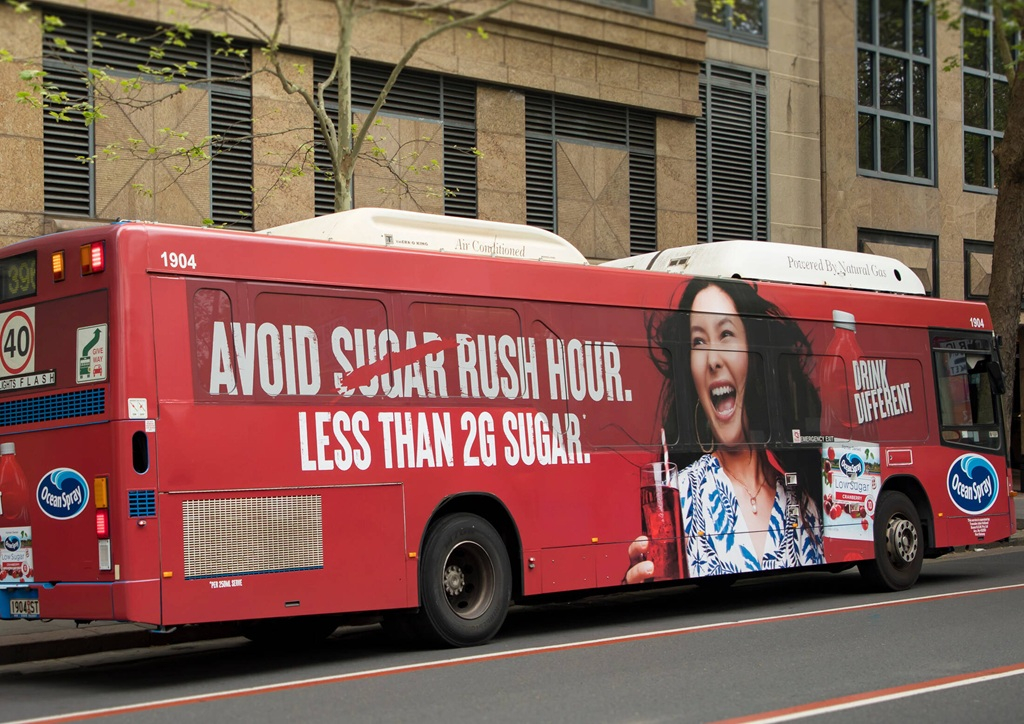На бортах автобусов: «Избегайте сахара в час пик. Менее 2 г сахара». Здесь напиток выступает как осознанный выбор против перегруза (как в пробках, так и в рационе).